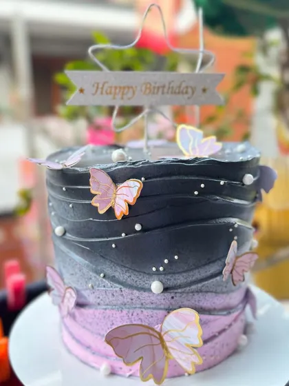 A stunning ombre cake in black and pink, decorated with delicate butterflies.