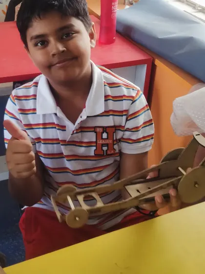 Thumbs up for a successful build! This student is happy with the rubber-powered car he made.