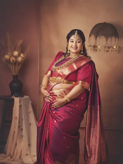 A beautiful standing portrait of the mom-to-be, her hand resting gently on her bump. The traditional styling and warm lighting create a stunning and regal image.