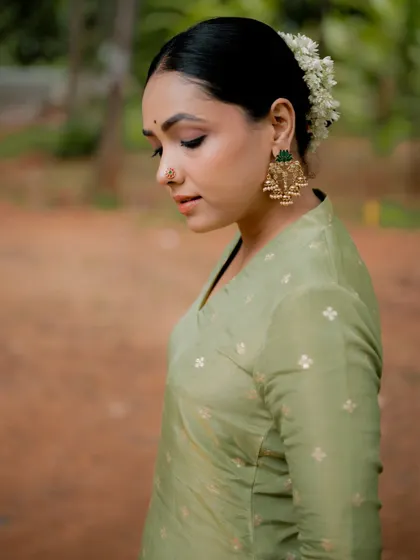 A smiling portrait of actress Anupama Gowda. The close-up shot captures her warm expression and highlights the traditional nose ring and earrings.