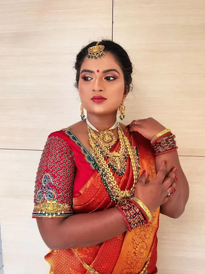 A poised shot of the South Indian bride, showcasing the complete look from the maang tikka to the layered necklaces.