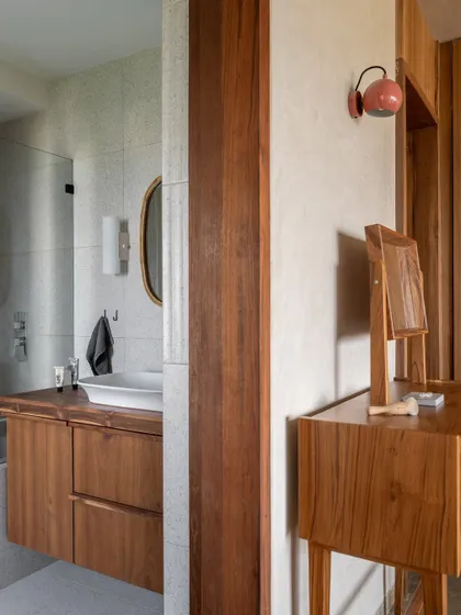 The master bedroom includes a simple teak vanity and a view into the attached bathroom. Every element is designed with privacy and utility in mind, creating a cohesive and peaceful personal space.