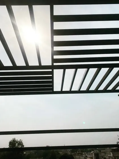 The sun shining through the geometric pattern of the pergola roof.