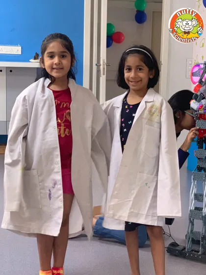 Two young scientists proudly sporting their lab coats, ready for a day of experiments and discovery. Getting to dress the part makes the experience even more special.