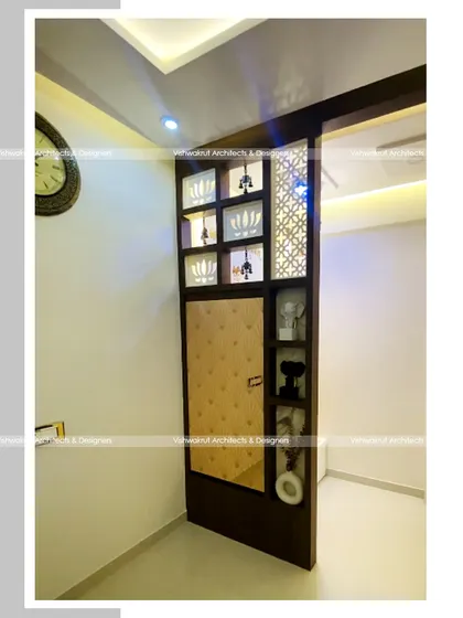 A view of the partition with a foldable dining table in its closed state. It functions as a beautiful decorative element with display niches and jali work, completely concealing the table.