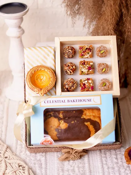 A beautiful jute basket filled with our handmade mithai, a buttery tea cake, and a traditional earthen diya.
