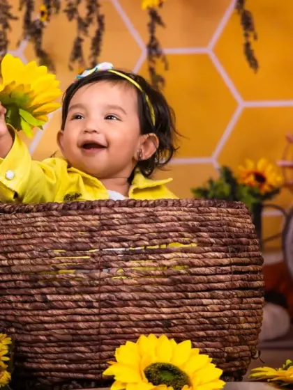 A bright and cheerful baby girl enjoying the sunflower props in our bee-themed shoot.
