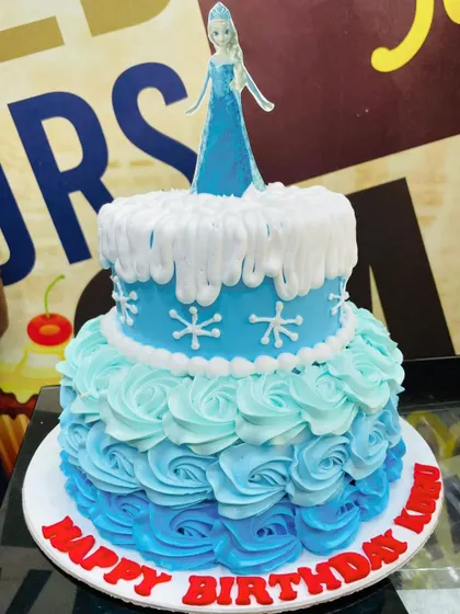 An icy blue 3kg Frozen cake with an Elsa topper and beautiful buttercream rosettes in an ombre pattern.
