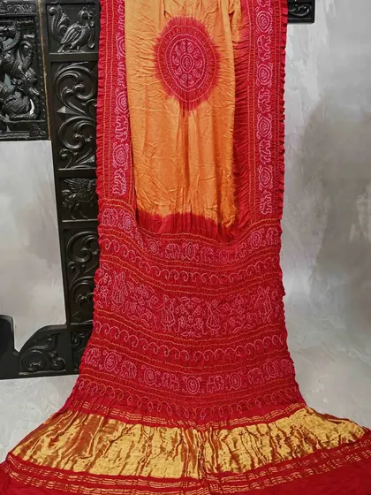 A fiery red and orange Bandhani saree. The crushed texture and vibrant colors are characteristic of this traditional craft, making it a perfect choice for festive occasions.