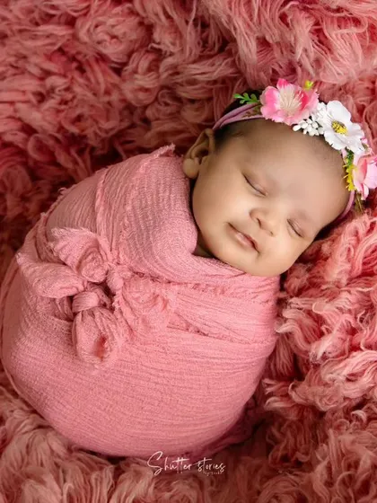 A smiling baby in a pink wrap on a matching textured rug. This shows how to create a simple yet impactful monochromatic setup.
