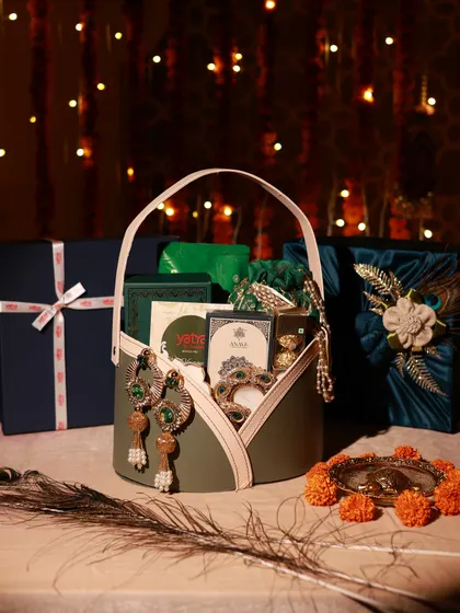 A complete look at one of the corporate Diwali gift sets for Yatra, featuring a hamper basket, a fabric-wrapped gift box, and a smaller branded box, all set against a festive backdrop.