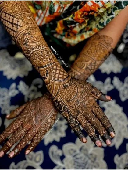 This design extends up the forearm, featuring intricate lattice work and traditional peacock and floral motifs. It’s a perfect choice for brides who want a grand and opulent henna design.