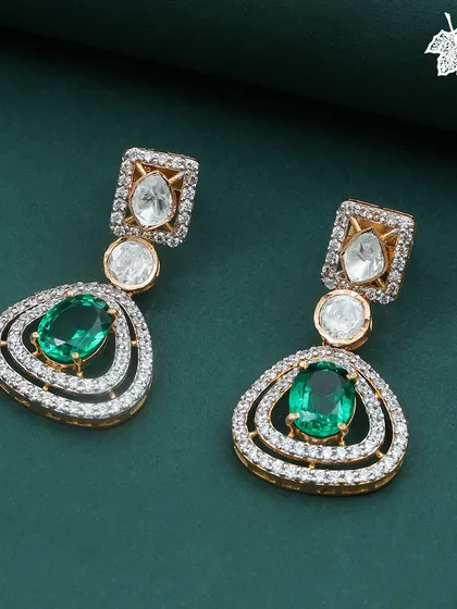 A close-up of the Green Grace earrings. Notice the double halo of diamonds surrounding the central emerald, and the elegant Polki diamonds that connect the drops, showcasing fine, detailed craftsmanship.