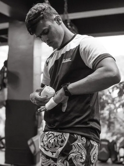 A fighter carefully wraps his hands, a crucial step to protect the knuckles and wrists before throwing punches.