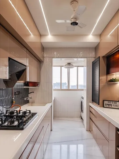 Another view of the galley kitchen, emphasizing the natural light coming from the utility balcony at the end, which makes the space feel bright and open.