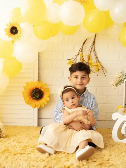 An older brother holds his baby sister during her first birthday photoshoot. We love capturing sibling bonds and including the whole family in the celebration.
