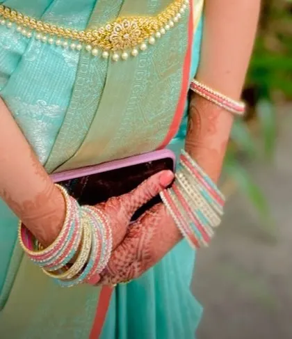 A close-up showing the intricate mehndi design and colorful bangles, part of the complete traditional look.
