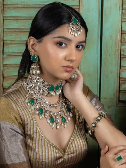The complete emerald Kundan bridal set, worn by a model. This look is perfect for a summer wedding, offering a fresh yet traditional feel.
