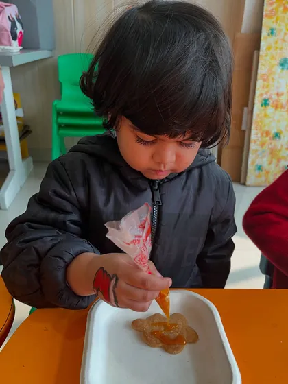 A child shows great focus while piping icing onto a cookie, a testament to how engaging our activities are.