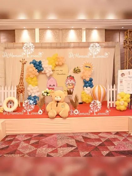A sweet and sunny stage for a twins' "First Trip Around the Sun" birthday, featuring a large teddy bear, giraffe prop, and cheerful sun details.