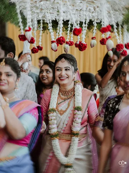 The bride makes her entrance, smiling brightly as she is escorted by her family under a canopy of flowers.