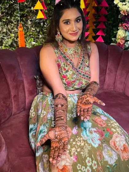 A happy bride displaying her full bridal mehndi. The design is a beautiful example of traditional Indian henna art, customized for her special day.