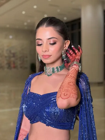 Another angle showcasing the beautiful henna and the contrast between the bold blue outfit and the soft, glamorous makeup.