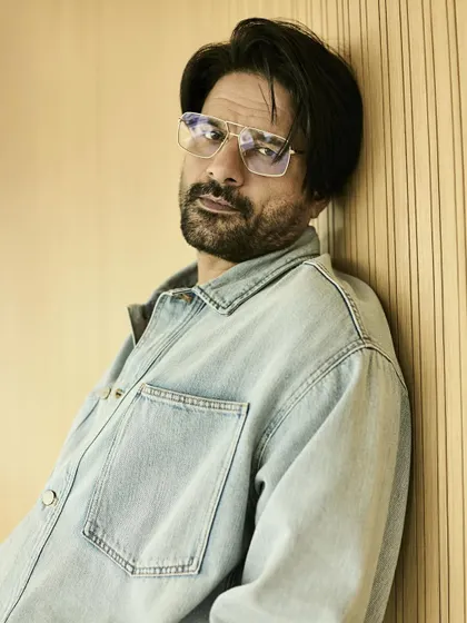 A close-up that highlights the cool, clear-framed glasses that add a smart touch to the casual denim look.