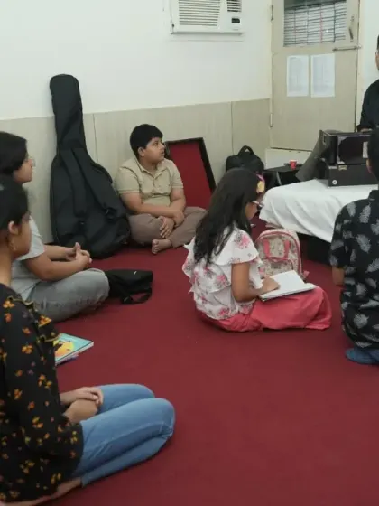 Students sit attentively in a group class, learning from their guru. We combine practical sessions with theory to provide a well-rounded music education.