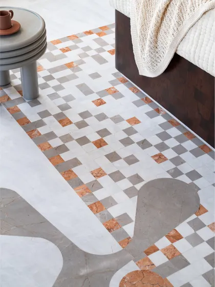The floor of the parents' bedroom in Gingham Dreams features a striking mosaic of marble in shades of grey, white, and terracotta, which flows from the bathroom into the bedroom.