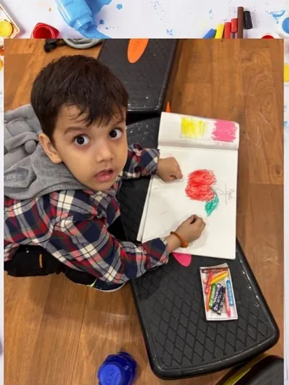 A very young artist carefully colors his drawing. We encourage creativity from the earliest ages, helping to develop fine motor skills and a love for art.