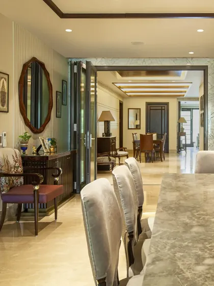 This perspective looks down the length of the marble dining table, through a set of folding glass doors into an adjacent living area. This demonstrates our approach to creating fluid, interconnected spaces within a home.