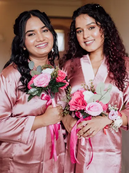 Two bridesmaids ready to celebrate, holding their bouquets. Their makeup is coordinated but tailored to their individual features.