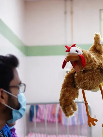 A chicken puppet has a conversation with a doctor. These playful interactions help humanize the hospital experience and create positive memories for everyone involved.