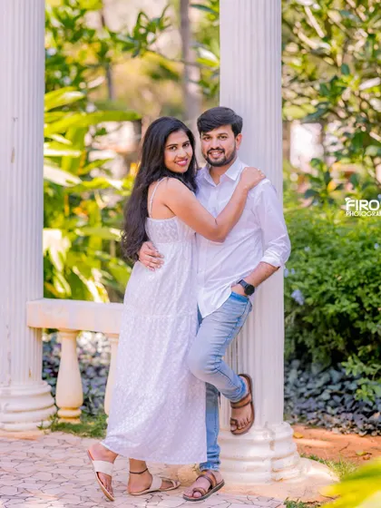 A happy, relaxed embrace in a garden with white pillars. The couple's all-white and denim outfits create a fresh, clean look for their pre-wedding photos.