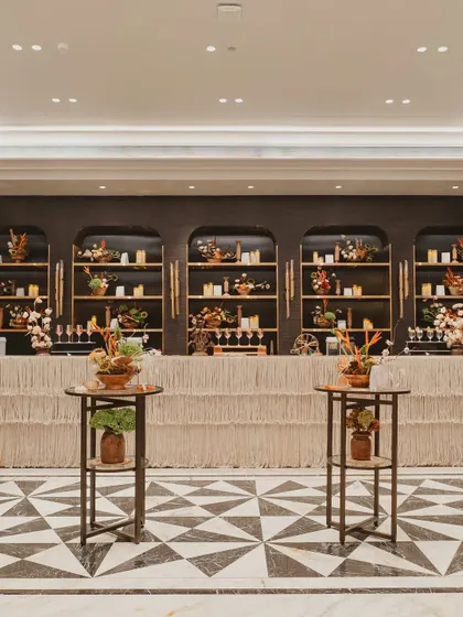 The bar design for the carnival event featured natural textures and a warm, candlelit back bar, blending seamlessly with the elegant and earthy decor.