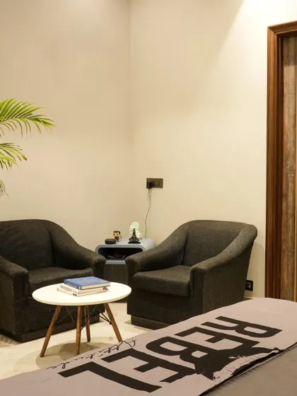 A small, cozy seating arrangement with two dark armchairs provides a quiet corner for relaxation in this son's bedroom.