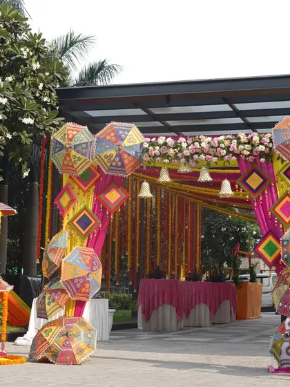 A closer look at the umbrella-themed entrance decor. The intricate patterns and vibrant colors of the umbrellas, combined with floral arrangements, create a unique and memorable entryway for any Mehendi or Sangeet event.