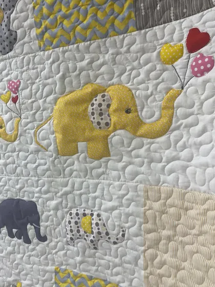 A close-up of the appliqué elephants, showing one holding a bundle of heart-shaped balloons.