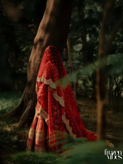 A mysterious and artistic shot of the bride veiled and standing in a forest. This kind of creative portrait adds a unique, cinematic element to the wedding album.