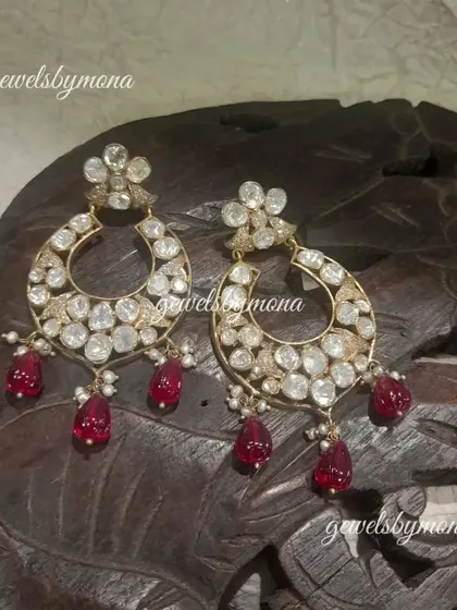 These polki chandbali earrings are a classic design, elevated with beautiful ruby drops. The crescent shape is filled with sparkling polki stones, making them a perfect accessory for weddings and festive occasions.