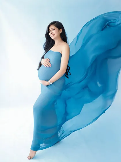 A beautiful and classic portrait with flowing fabric. The vibrant blue of the gown creates a stunning visual against the soft background.