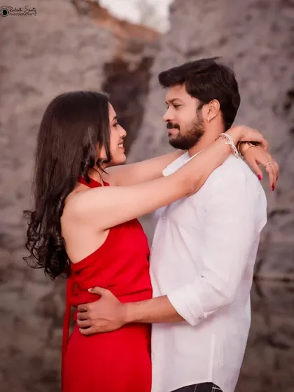 A happy and affectionate pre-wedding photo. The couple's embrace and joyful expressions against a natural rock background make for a beautiful and candid love portrait.