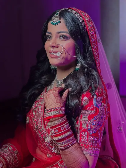 The final look with the dupatta set. The purple lighting adds a touch of drama, but her glowing skin and classic red bridal makeup shine through.