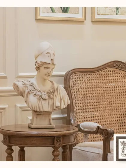 This classical bust depicts the ancient Greek goddess Athena. Placed on a simple wooden side table, it brings a touch of intellectual and historical elegance to the room.