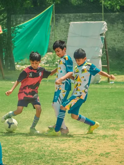 A scramble for the ball involving four young players.