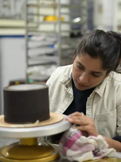 Focused on the details. Here I am, working on a chocolate-wrapped cake, ensuring the finish is smooth and perfect.