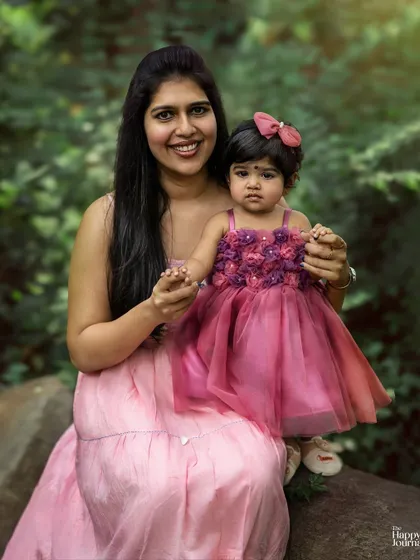 A mother and daughter portrait taken outdoors. Their matching pink outfits and the natural setting create a soft and lovely image.
