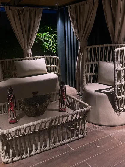 A close-up of the lounge at night. The soft lighting highlights the intricate details of the woven furniture and creates a cozy, intimate mood.