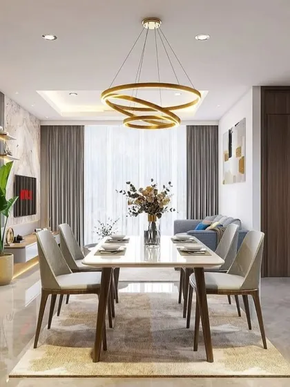 A bright and spacious living-dining area with a large dining table, modern ring chandelier, and a clear view of the TV unit in the background.